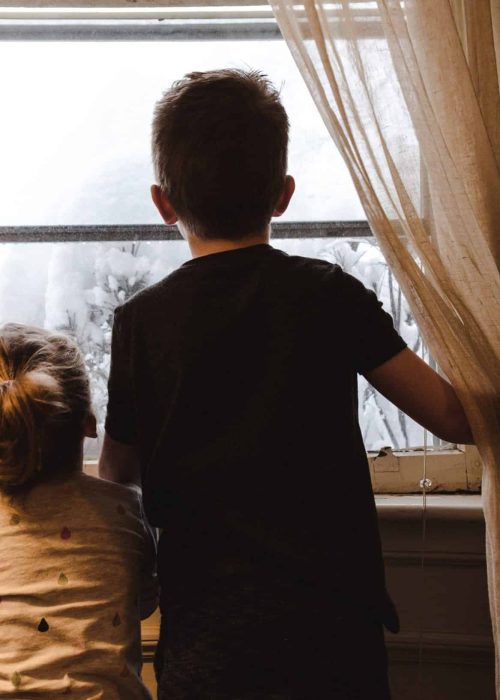 children-looking-out-of-the-window-at-their-home