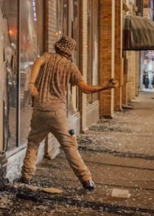 man-throwing-brick-through-window